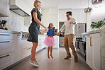 Mother, father and girl jumping in dance in a house kitchen or home interior for fun, play or creative bonding. Happy, smile and family or man and woman holding hands with child in energy performance