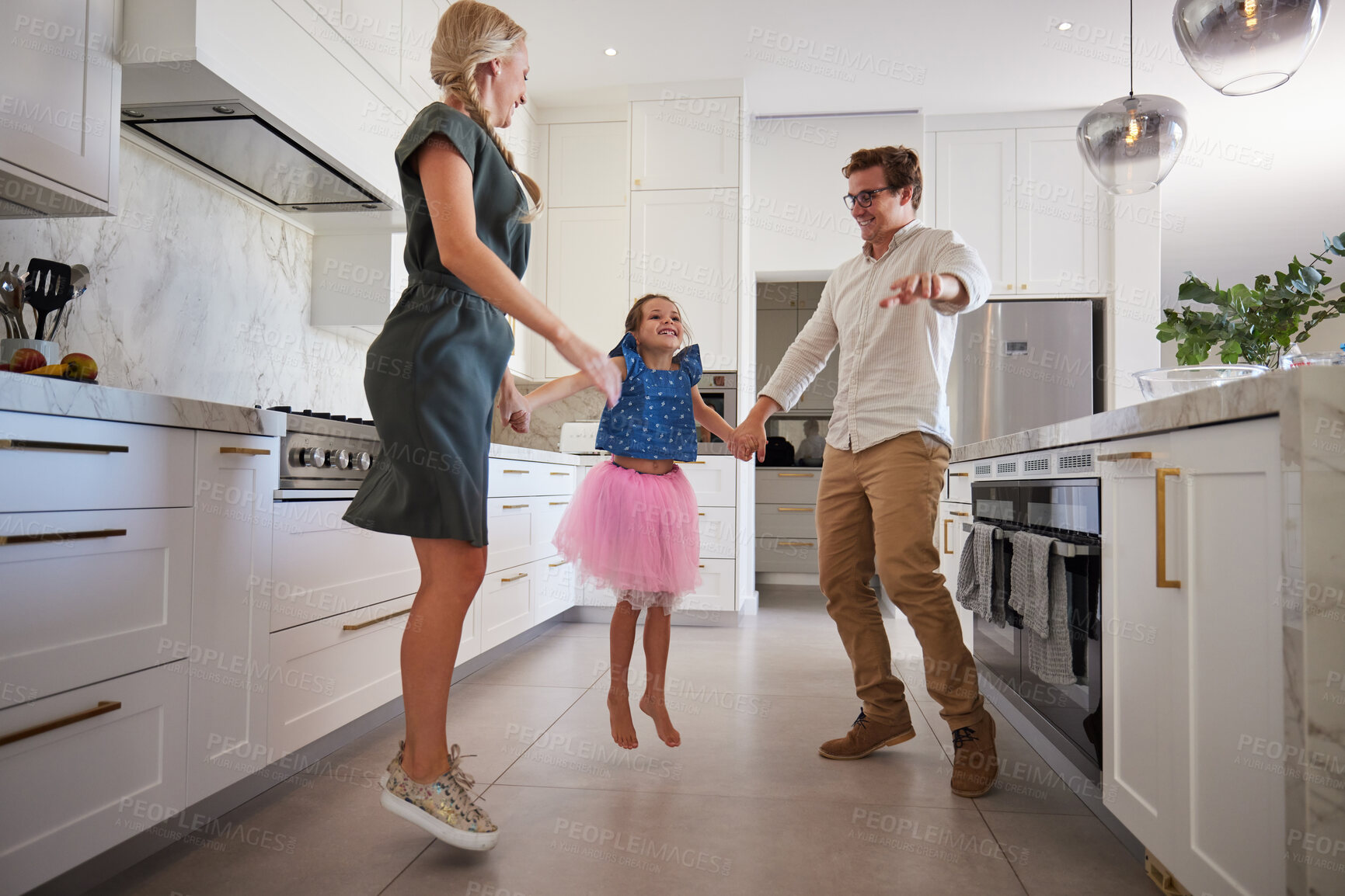 Buy stock photo Mother, father and girl jumping in dance in a house kitchen or home interior for fun, play or creative bonding. Happy, smile and family or man and woman holding hands with child in energy performance