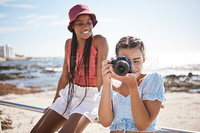 Buy stock photo Summer, beach and photographer with camera, young girl taking a photograph. Friends, fun and happy teenagers on holiday by the sea with a scenic ocean view. Portrait of girls, photography and nature