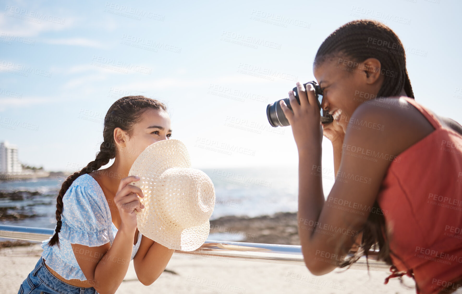 Buy stock photo Photographer, woman and model at the beach in summer shooting a creative, freedom and happy outdoor pictures. Photography, smile and fun girl holding a camera with focus on female and ocean backdrop