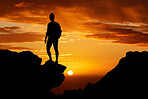 Sunset, hiking and silhouette of a man on top of the mountain during an adventure journey in africa. Freedom, orange sky and guy standing on a cliff while trekking in nature on a summer evening.