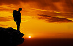 Dark silhouette, mountain travel and sunset on hiking adventure in nature, sky orange while trekking with backpack and freedom on cliff. Person on holiday in Africa walking on summer journey