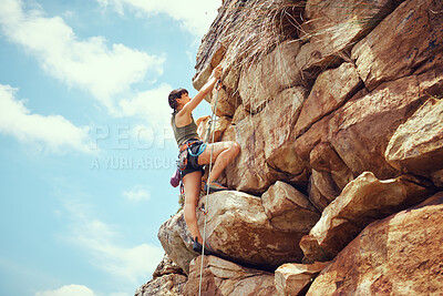 Buy stock photo A woman in nature rock climbing, training and fitness outdoors on a sunny day with climbing equipment. A female, strong and healthy athlete doing exercise, physical activity and extreme climbing. 