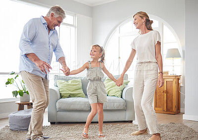 Buy stock photo Love, retirement and family dancing in home living room together to bond with cute girl child. Happy senior grandmother and grandfather enjoy fun in family home with young grandchild.

