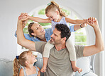 Happy family, relax and bonding on a sofa in their home, cheerful and having fun. Young parents being playful and loving with their girls, enjoying a game on the weekend with fun mother and father