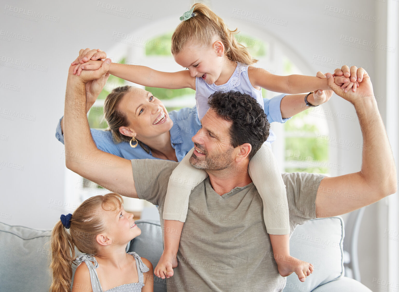 Buy stock photo Happy family, play and bonding on a sofa in their home, cheerful and having fun. Young parents being playful and loving with their girls, enjoying a game on the weekend with fun mother and father