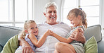Happy family, retirement and old man playing with children on the sofa bonding, happiness and laughing together. Smile, elderly and grandpa with little girls enjoying quality time on a couch at home