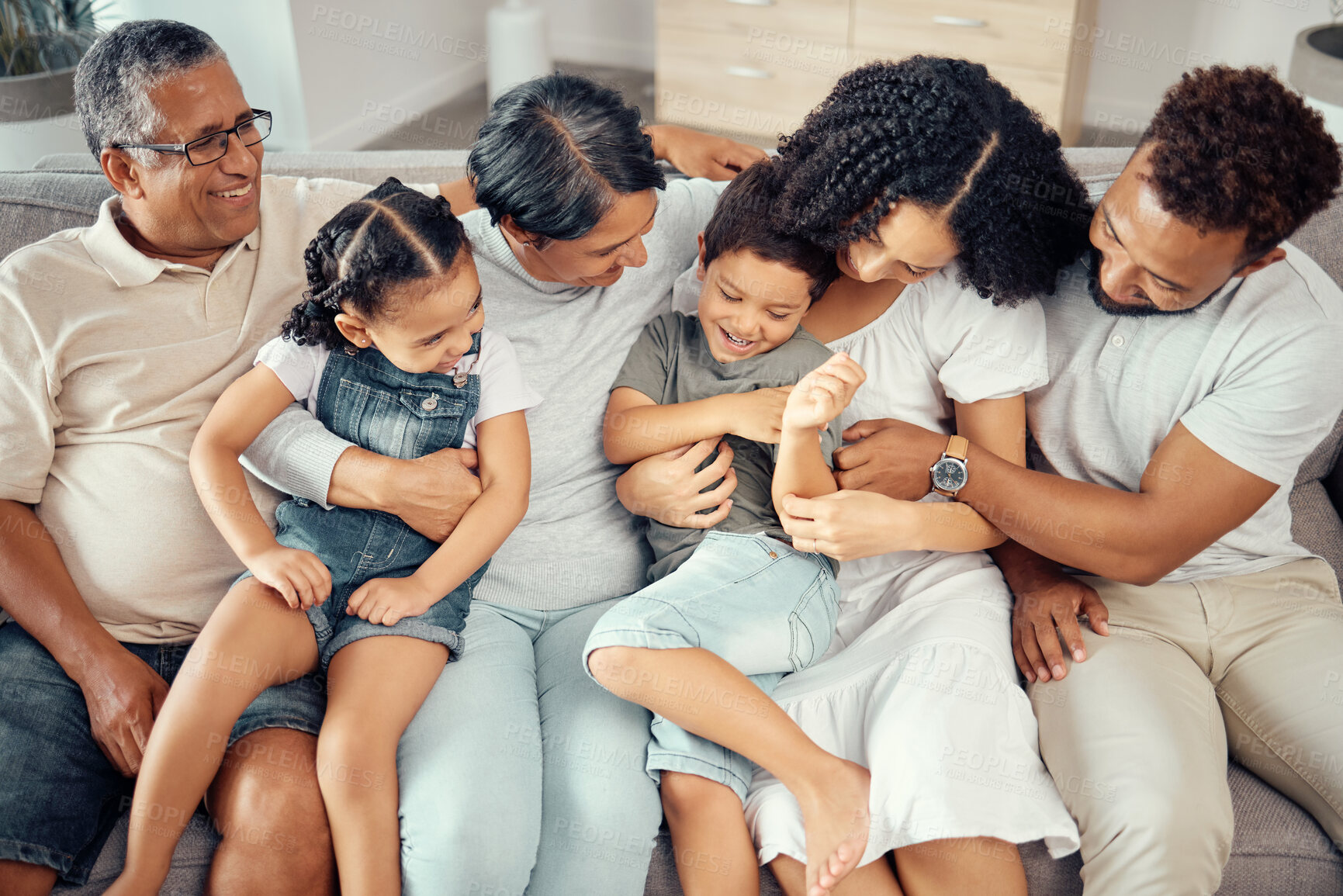 Buy stock photo Big family, bonding fun and love of children, parents and grandparents while sitting together on the sofa at home. Happy, laughing and tickling while sharing a special moment with men, women and kids