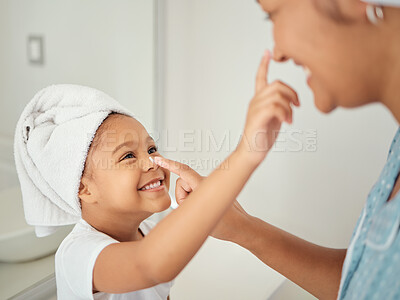 Buy stock photo A happy Mom, smiling child using cream and teaching skincare beauty routine to girl in a bathroom. Mother helping her daughter to learn to help her skin, hair and body healthy with self care products