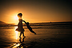 Sunset, beach and silhouette of a mother and girl playing on the sand while on summer vacation. Family, fun and happy woman swinging her child in nature by the ocean while on holiday in south africa.