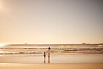 Girl and mother walking in the water at the beach during sunset on summer family vacation. Young daughter and her mom spending quality time together by the ocean during the dusk on travel holiday