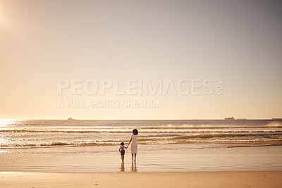 Buy stock photo Girl and mother walking in the water at the beach during sunset on summer family vacation. Young daughter and her mom on sand together by the ocean during the dusk on travel holiday with mockup space