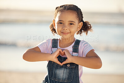 Buy stock photo Girl at beach make heart sign with hands, happy and smile against blurred nature background. Young female child with expression of happiness, makes love icon, gesture with fingers by the ocean or sea