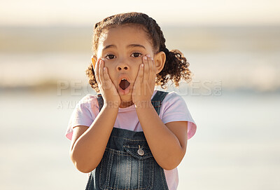 Buy stock photo Wow, children and hands on the face of a girl on the beach looking surprised or shocked outside during summer. Kids, youth and surprise with a little female child feeling shock while outdoor alone