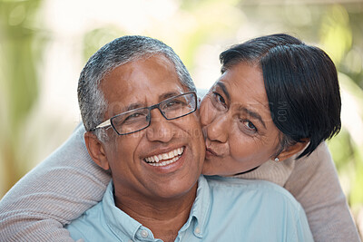 Buy stock photo Love, kiss and happy senior couple sharing commitment, hug and affection while sitting together showing smile. Portrait of elderly indian man and woman enjoying retirement and free time to bond 
