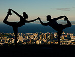 Silhouette of couple stretching and doing yoga at sunrise in the city. Man and woman training, exercising and doing workout together at sunset. People holding hands in yoga pose with city background