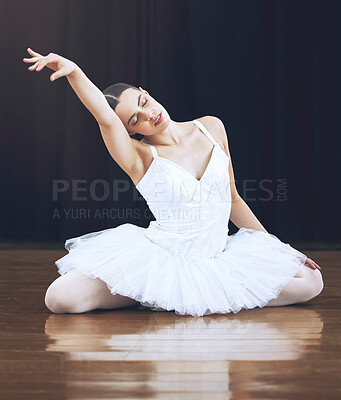 Buy stock photo Ballerina sitting on the floor in a studio or on a stage, in a pose during dance. Young ballet dancer with her hand up while dancing or posing during theatre performance of beauty, grace and elegant