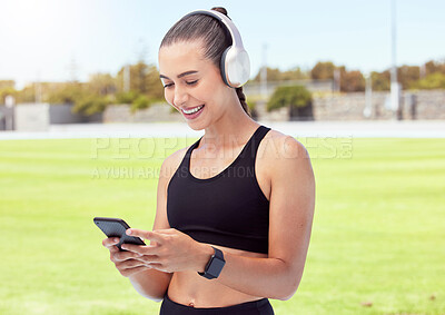 Buy stock photo Woman athlete with phone, happy and smile with headphones and listening to music and reading a text message in the city. Young female enjoy a break from exercising outdoor and streaming audio or meme