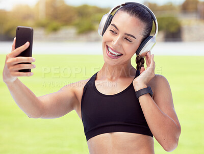 Buy stock photo Phone, woman and fitness influencer taking a selfie at training, running and workout outdoors on sports racetrack. Smile, healthy and happy girl in headphones sharing fitness journey on social media