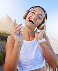 Fitness, headphones and woman outdoor listening to music for wellness podcast while training or doing workout exercise on blue sky and lens flare. Young person with 5g audio for exercise on mountain