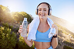 Headphones, workout and music streaming of a happy woman after exercise in nature by mountains. Fitness, health and sport person after training drinking water with smile feeling free with happiness 