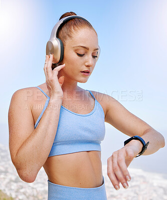Buy stock photo Fitness, runner and woman on time by her smartwatch as she monitors her performance, heartbeat and pulse outdoors. Headphones, health and girl running in summer streaming music, radio song or podcast