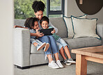A mother with children on couch with tablet to watch educational shows and streaming music. Foster or adoption parent with kids in living room watch cartoons, playing online games and homeschooling. 