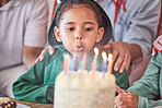 Birthday, cake and girl with candles, happy and excited at a party celebration with family. Children, event and birthday party fun by child blowing and enjoy birthday cake candle and her special day