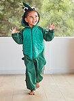 Child, smile and excited in halloween dinosaur costume at home playing role and having fun at party. Happy kid being playful with fantasy character in living room mimic animal actions ready to roar. 