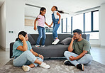 Family, energy and kids jumping on home sofa with tired parents struggling with naughty, hyperactive and playing children. Woman and man with ADHD, noisy and laughing girls, friends or fun twins