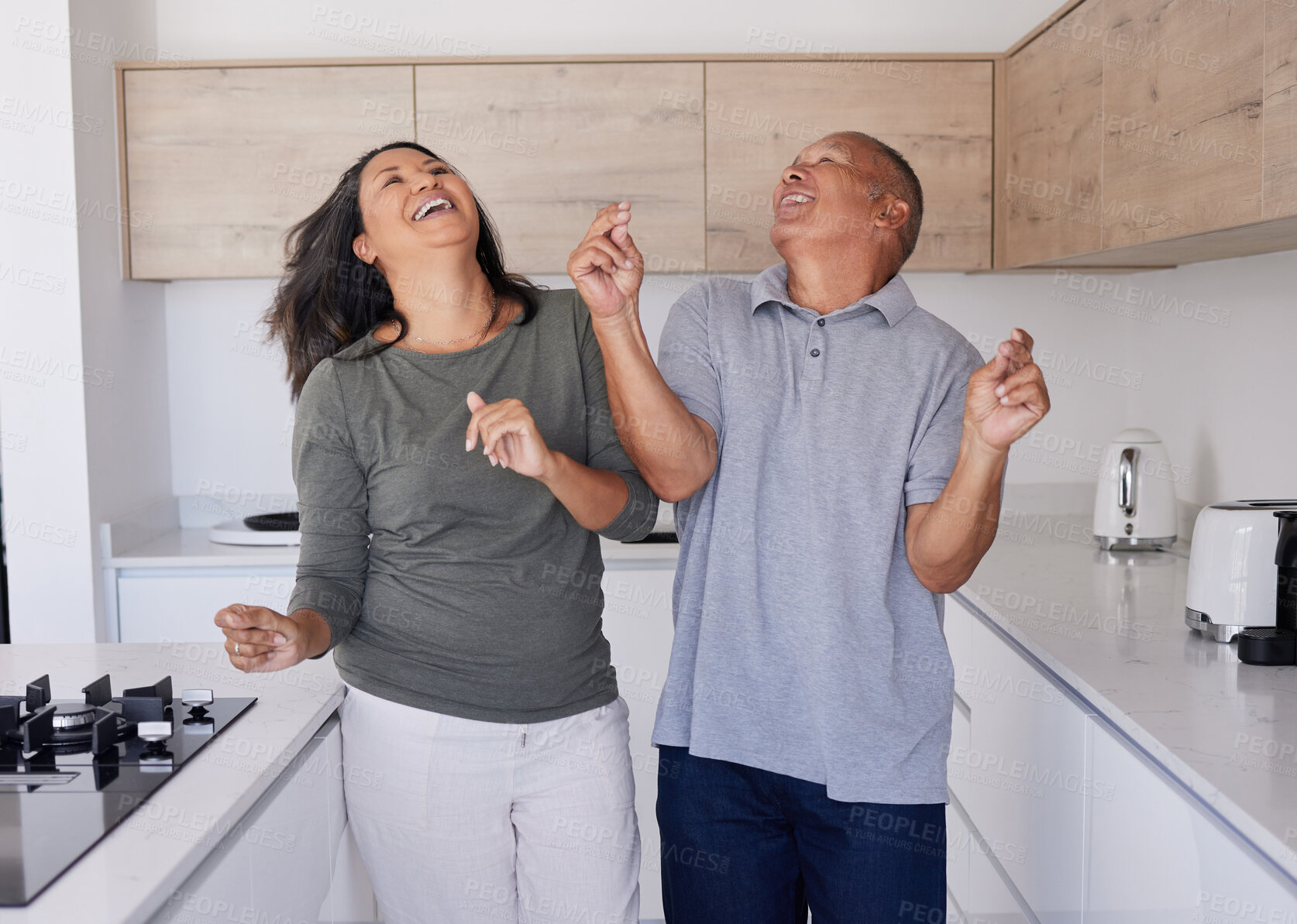 Buy stock photo Couple, dance and freedom with a senior man and woman dancing together in the kitchen of their home. Happy, smile and free with an elderly male and female pensioner having fun and bonding in a house