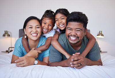 Buy stock photo Portrait of a happy Asian family on the bed with a smile on their face. Multicultural Indian family in their bedroom smiling, laughing and having fun. Loving mom, dad and kids bond together at home