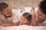 Mother, father and girl in bed in house bedroom, home interior and bonding on a morning. Family smile, happy and love bond parents or man and woman with young child in security, support or trust
