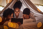 Family, tablet and online streaming with kids for a bedtime story, movie or cartoon for educational fun while in a blanket fort. Brazilian woman with boy and girl child at night reading on internet