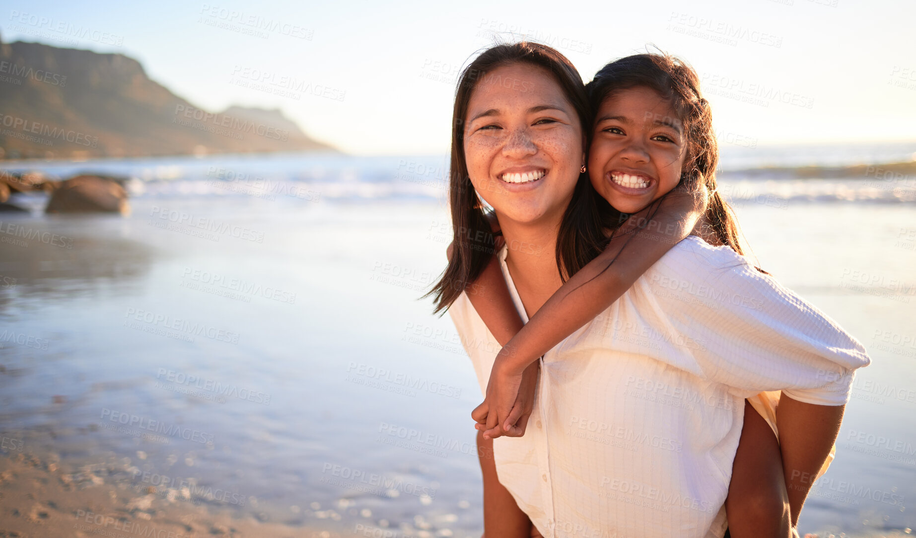 Buy stock photo Happy mother and girl have fun together at the beach in the sun on summer vacation. Carefree woman carrying excited child while bonding outdoor. Single mom enjoy quality time with kid at the ocean