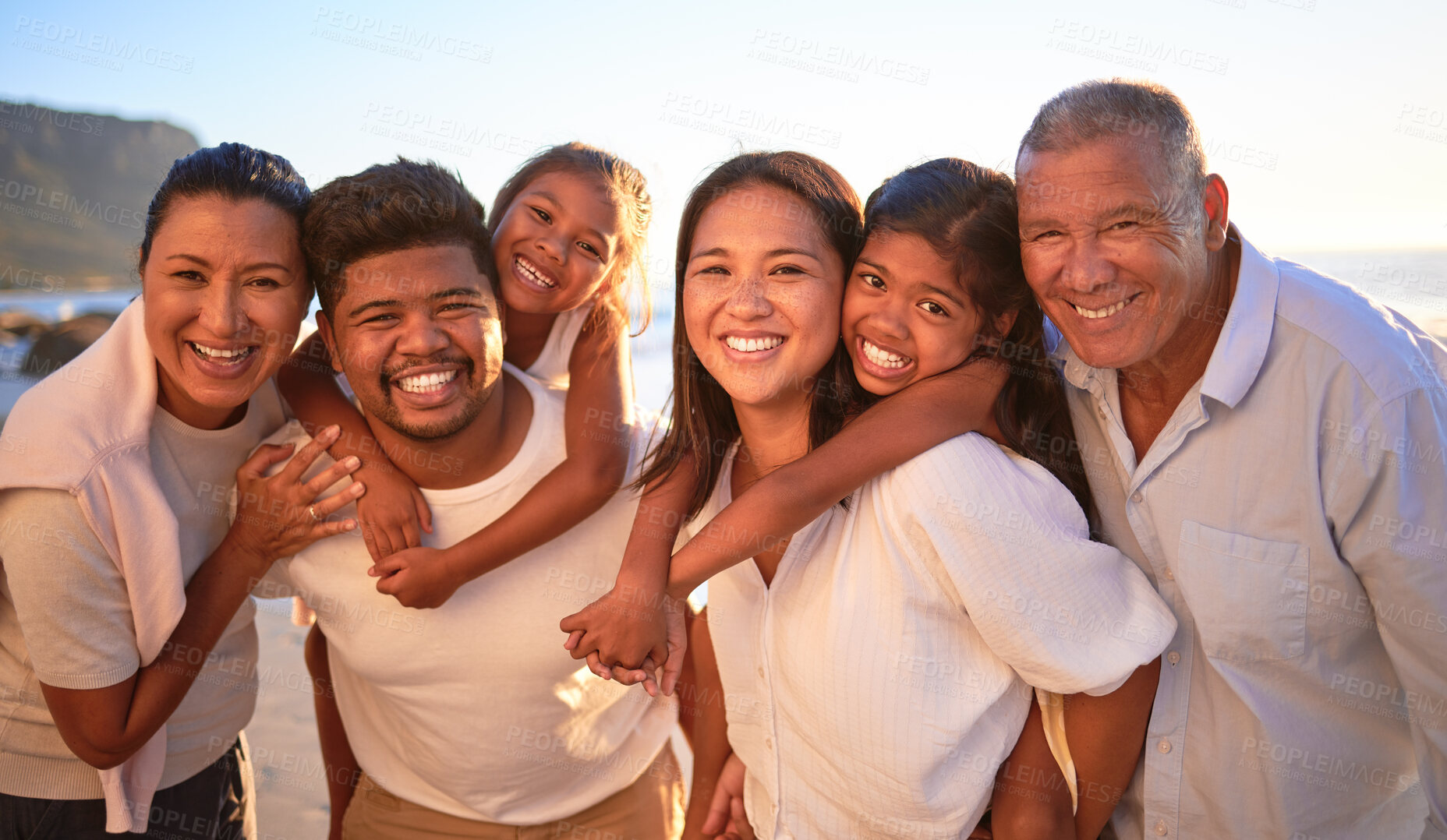 Buy stock photo Portrait of happy family with children smile and hug together on a sunset beach. Adorable little kids bonding with mother, father, grandmother and grandfather outdoor on summer vacation at the ocean
