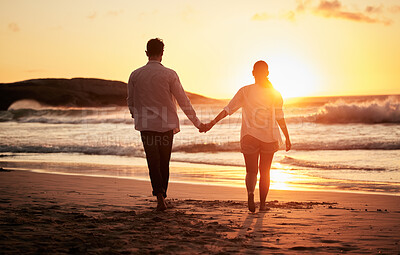 Buy stock photo Sunset, couple holding hands and walking by the beach with a beautiful twilight. Love, romance and happy man and woman spending time together with affection by ocean, sea and sandy shore on holiday.