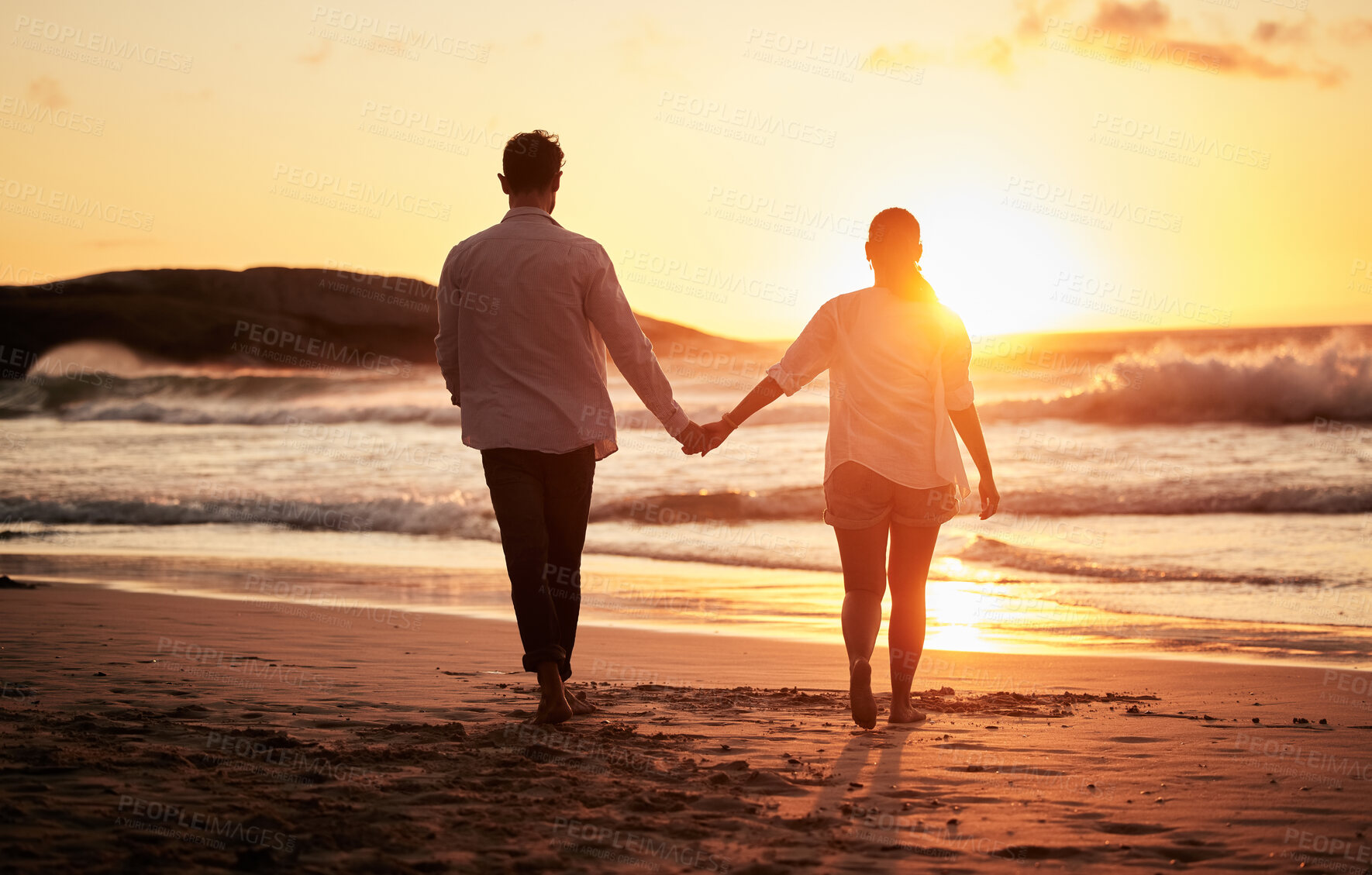 Buy stock photo Sunset, couple holding hands and walking by the beach with a beautiful twilight. Love, romance and happy man and woman spending time together with affection by ocean, sea and sandy shore on holiday.