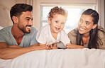 Happy, love and parents with their baby on bed in the bedroom bonding, playing and relaxing at home. Happiness, smile and couple laying with their child in hotel room while on family holiday together