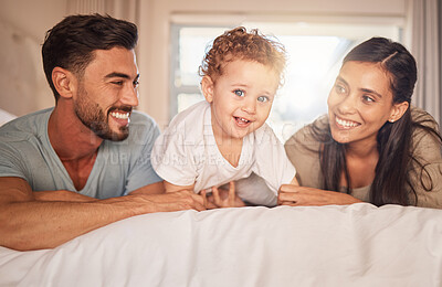 Buy stock photo Happy, love and parents with their baby on bed in the bedroom bonding, playing and relaxing at home. Happiness, smile and couple laying with their child in hotel room while on family holiday together