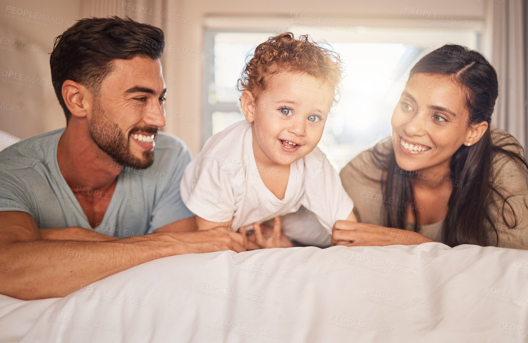 Buy stock photo Happy, love and parents with their baby on bed in the bedroom bonding, playing and relaxing at home. Happiness, smile and couple laying with their child in hotel room while on family holiday together