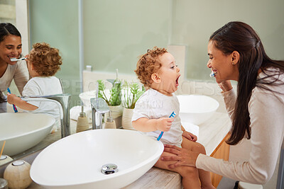 Buy stock photo Mom teaching baby to brush its teeth, on the bathroom counter in home and a clean smile on her face. Healthy oral hygiene for kid means using child friendly toothpaste, toothbrush and dental routine 