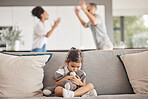 Depression, stress or child trauma for girl with teddy bear on living room sofa and listening to fight, scream or shouting parents. Burnout, anxiety or mental health kid with divorce father or mother