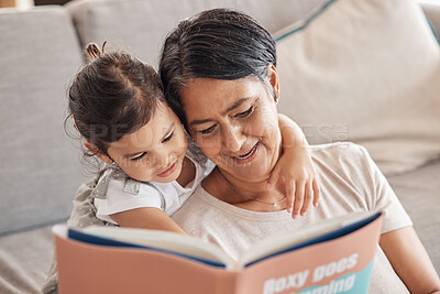 Buy stock photo Education, learning and girl and grandmother reading a book on a sofa, relax and bonding in living room. Children, love and storytelling by senior woman enjoying fantasy story with curious grandchild