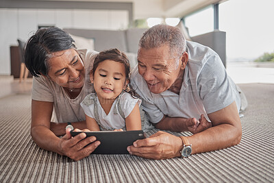 Buy stock photo Relax, grandparents and cartoon on tablet with child on home floor together in the Philippines. Filipino family bonding time with grandfather, grandmother and grandchild watching animation online.

