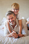 Family, love and children with a father and son lying on bed together in a bedroom of their home. Face, happy and smile with a portrait of a man and his boy child in their house to relax on a morning