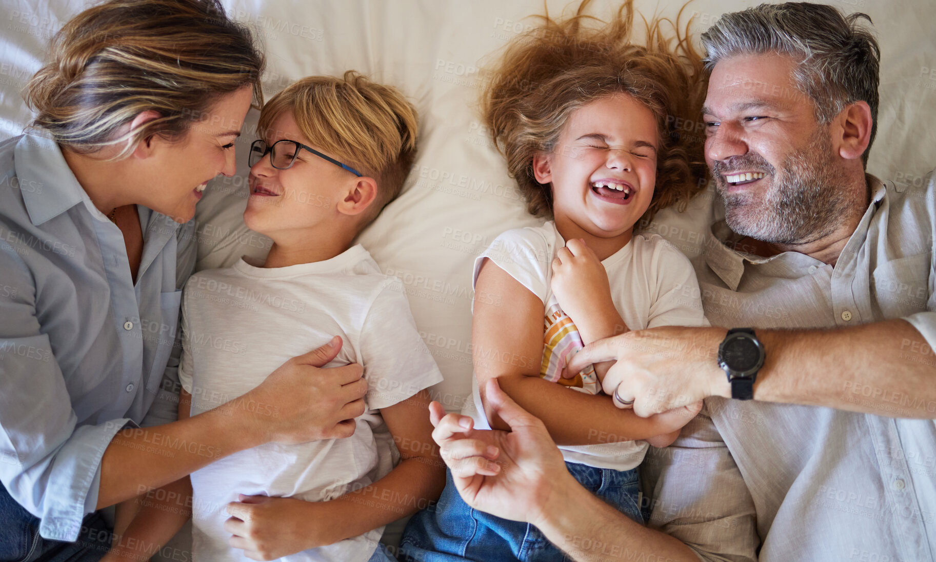 Buy stock photo Top view, parents and children on bed relax, fun and laugh together on weekend. Family, love and happy man and woman in bedroom with kids, daughter and son being playful, embrace and bonding at home.