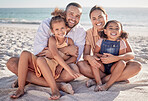 Happy, family and relax with smile on beach for summer vacation and bonding time together in nature. Mother, father and children relaxing on sandy shore smiling for holiday break or weekend travel