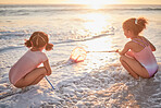 Children, girls and fishing with nets at the beach in playful fun on summer vacation in the outdoors. Little girl siblings playing and exploring the ocean in low tide to catch fish in the sunset