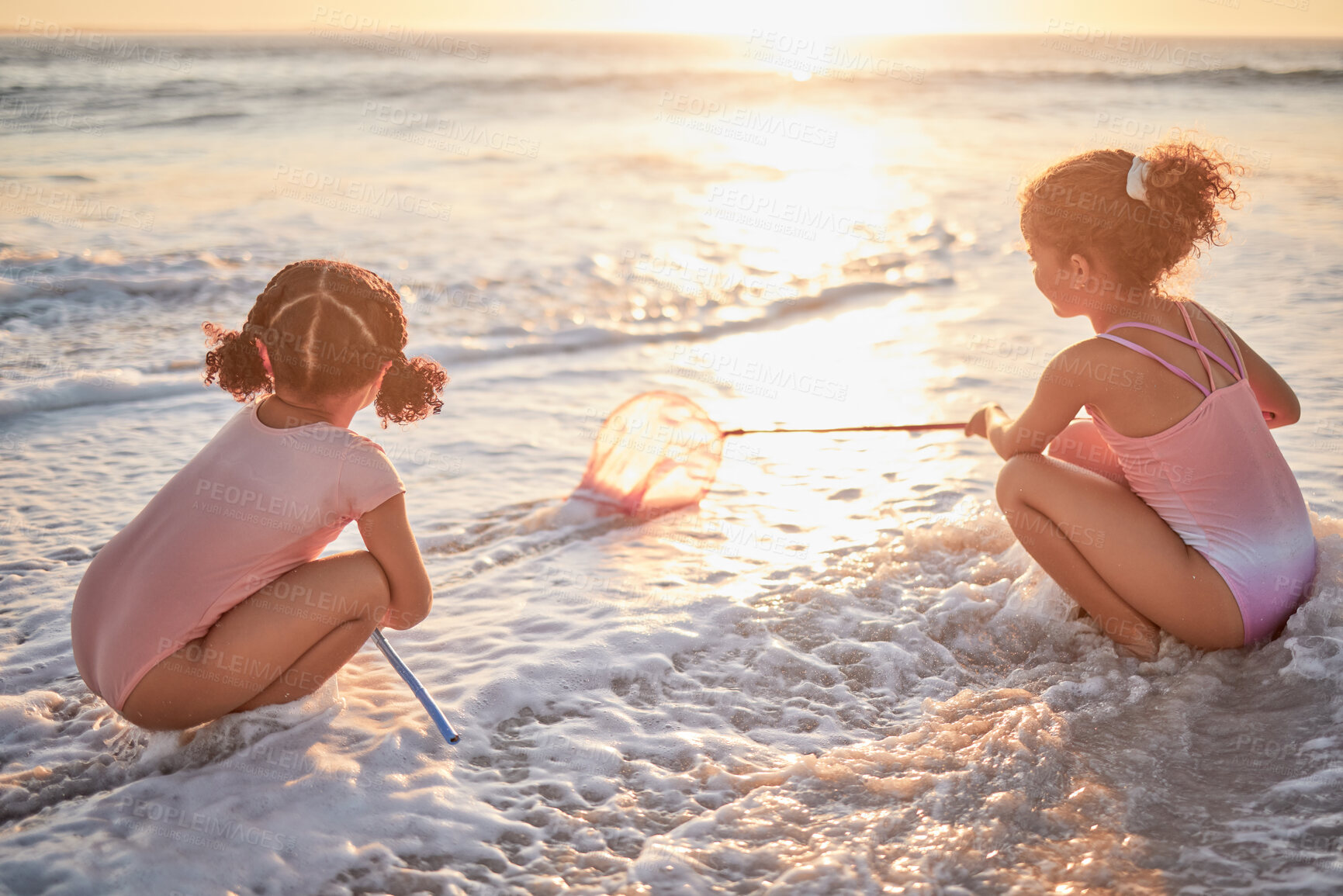 Buy stock photo Children, girls and fishing with nets at the beach in playful fun on summer vacation in the outdoors. Little girl siblings playing and exploring the ocean in low tide to catch fish in the sunset
